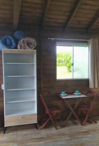 a room with a table and chairs and a window at Koa Cabana praia do luz in Imbituba