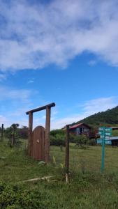 a wooden structure in a field next to a sign at Koa Cabana praia do luz in Imbituba