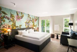 a bedroom with a large bed and a living room at ANA Living Karlsruhe by Arthotel ANA in Karlsruhe