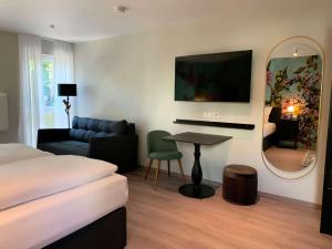 a hotel room with a bed and a table and a mirror at ANA Living Karlsruhe by Arthotel ANA in Karlsruhe