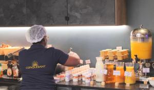 a woman behind a counter in a kitchen preparing food at Best Western Plus Le Conquerant Rouen Nord in Bois-Guillaume