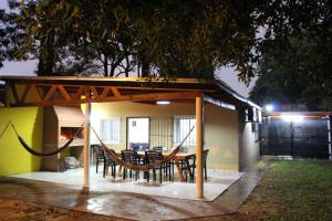 un patio avec une table et des chaises sous un toit dans l'établissement Casa El Sueño, à Ituzaingó