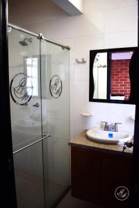 y baño con ducha acristalada y lavamanos. en Hotel Boutique Rosa María, en Iza
