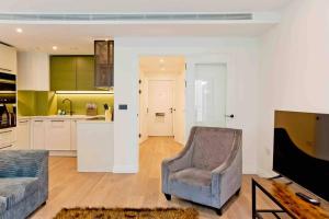 a living room with a couch and a chair and a kitchen at Modern 1 bedroom flat with balcony in Chelsea in London