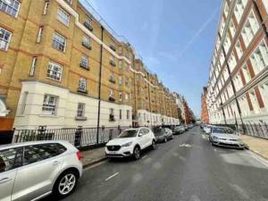 une rangée de voitures garées dans une rue abritant des bâtiments dans l'établissement Fitzrovia 2 Bed modern +Lift central London, à Londres