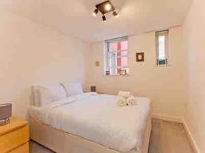 a white bedroom with a large white bed and a window at Fitzrovia 2 Bed modern +Lift central London in London