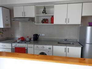 a kitchen with white cabinets and a sink and a dishwasher at Los Juncos Jujuy in San Salvador de Jujuy