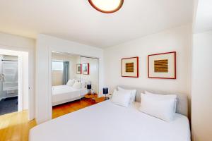 a white bedroom with a white bed and a couch at Waikiki Haven in Honolulu