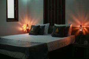 a bedroom with a bed with pillows and two lights at Charming dark lodge in river in Weligama