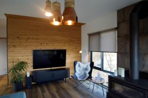 ein Wohnzimmer mit einem Kamin und einem TV in der Unterkunft Baden House - Freycinet Holiday Houses in Coles Bay