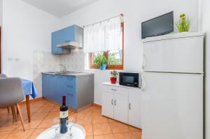 a kitchen with a refrigerator and a table with a bottle of wine at Apartments by the sea Fazana - 6957 in Marana