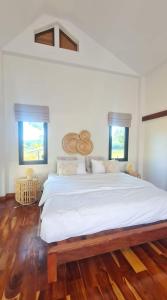 a large white bed in a room with wooden floors at Punpawn ปั๋นปอนด์ Farm Stay in Chiang Saen