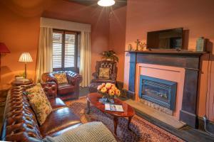 a living room with leather furniture and a fireplace at St Bernards Presbytery- Hartley Historic Site in Hartley