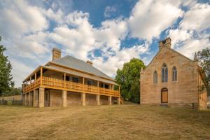 a large brick building with a porch on a field at St Bernards Presbytery- Hartley Historic Site in Hartley