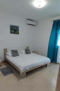 Schlafzimmer mit einem weißen Bett und blauen Vorhängen in der Unterkunft Family friendly apartments with a swimming pool Vinisce, Trogir - 12676 in Vinišće