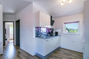 uma cozinha com armários brancos e uma janela em Apartments with a parking space Bilice, Krka - 13545 em Sibenik