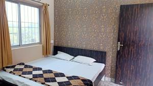 um quarto com uma cama com um cobertor xadrez e uma janela em Hotel K2 Near Chaibasa em Chāībāsa