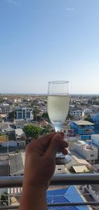 une main tenant un verre de vin blanc sur un balcon dans l'établissement Jade Aparts Salinas, à Salinas