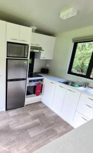 a kitchen with white cabinets and a stainless steel refrigerator at Private Country Cottage in Paraparaumu