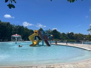 un parque infantil en una piscina con gente en el agua en Apartamento Iloa residence en Barra de São Miguel