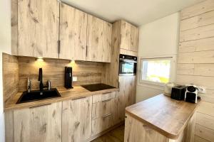 uma cozinha com armários de madeira e um lavatório em Bright apartment - close to the slopes em Demi-Quartier