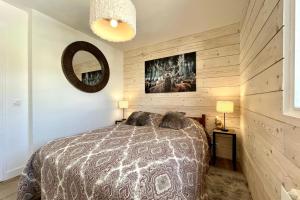 1 dormitorio con cama y espejo en Bright apartment - close to the slopes, en Demi-Quartier