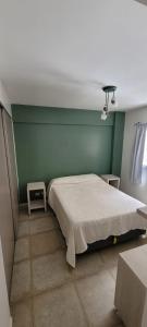 - une chambre avec un lit et un mur vert dans l'établissement Confortable Departamento en Mar del Plata, à Mar del Plata