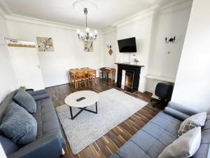a living room with a couch and a table at Newly Refurbished 2 Bedroom Flat - Long stays AVL in Norbury