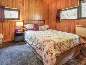 1 dormitorio con 1 cama en una habitación con paredes de madera en Dornie Lodge, en Beauly