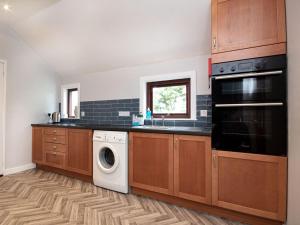 a kitchen with wooden cabinets and a washer and dryer at Auld House in Brora
