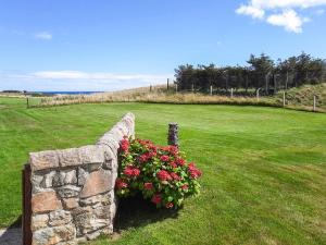 a stone retaining wall with flowers in a field at Auld House in Brora