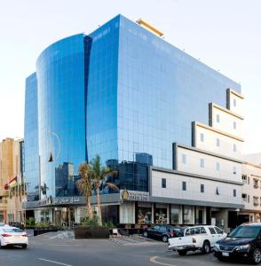ein großes Glasgebäude mit Autos auf einem Parkplatz in der Unterkunft فندق ستي فيو- City View Hotel in Dschidda