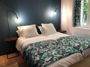 a bed in a bedroom with two lamps on the wall at Charmant Gîte Familial Rénové avec 3 Chambres, Cheminée et Jardin, Proche Le Mans - FR-1-410-332 in Le Mans