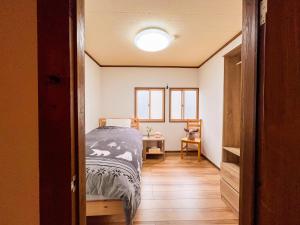 a bedroom with a bed and a table with a chair at KONAYUKI in Myoko