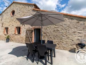 a table with an umbrella in front of a building at Gîte de Charme entre Cholet et Puy du Fou avec Terrasse et Équipements Complets - FR-1-622-33 in Saint-Christophe-du-Bois +4 photos