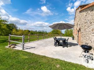a patio with an umbrella and a table and chairs at Gîte de Charme entre Cholet et Puy du Fou avec Terrasse et Équipements Complets - FR-1-622-33 in Saint-Christophe-du-Bois