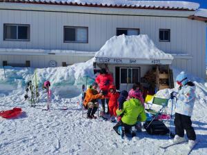 Guest House Shiroikiseki في توياما: مجموعة اطفال واقفين في الثلج امام مبنى