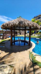 a swimming pool with a thatched gazebo at Beach Living Vista Mar - 3 Quartos - Pé na Areia in Aquiraz