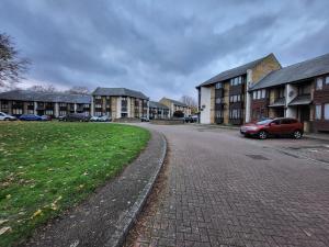 une voiture rouge garée sur le côté d'une rue dans l'établissement Manor Place Apartment Thamesmead, à Thamesmead