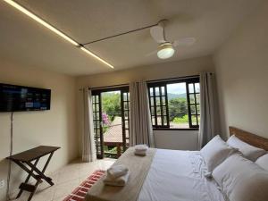 a bedroom with a bed and a table and windows at Beautiful view room in Angra dos Reis