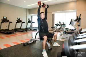 a man lifting a barbell in a gym at Citadines Keqiao Shaoxing in Shaoxing