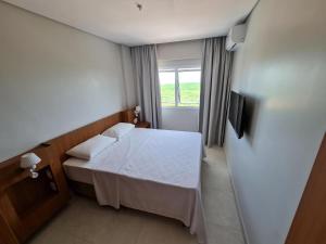 um pequeno quarto com uma cama e uma janela em Apartamento em Salinas Exclusive Resort em Salinópolis