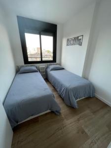 a bedroom with two beds and a window at UruSamKa Apartamento 2 dormitorios en Centro MoNteVidEo in Montevideo