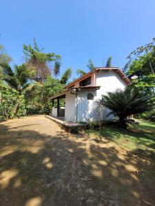 uma pequena casa branca com uma árvore em frente em Casa da Neia em Paraty