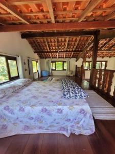 uma cama grande num quarto com pisos e janelas em madeira em Casa da Neia em Paraty