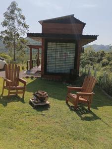 two chairs sitting in the grass in front of a cabin at Casinha na serra para até 4 pessoas in Nova Petrópolis +6 photos