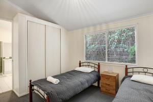 two beds in a bedroom with a window at Amaroo House in Point Lookout