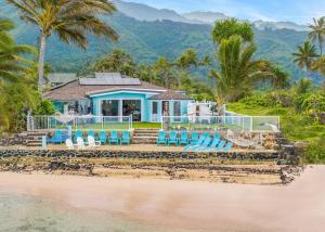a house on the beach with chairs and palm trees at Corner Luxury Ethereal Hawaii Beachfront Estate for Monthly Rental with Private Beach & 3 Beachfront Jacuzzis & Snorkeling Reef & Jurassic Park Film Site in Punaluu