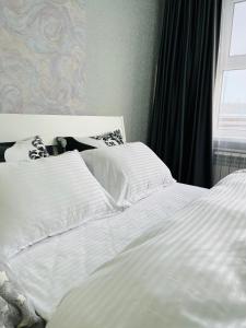 2 camas blancas en un dormitorio con ventana en Металлургов 20, en Temirtaū