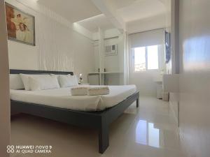 um quarto com uma cama grande e lençóis brancos em Mecasa Hotel em Boracay